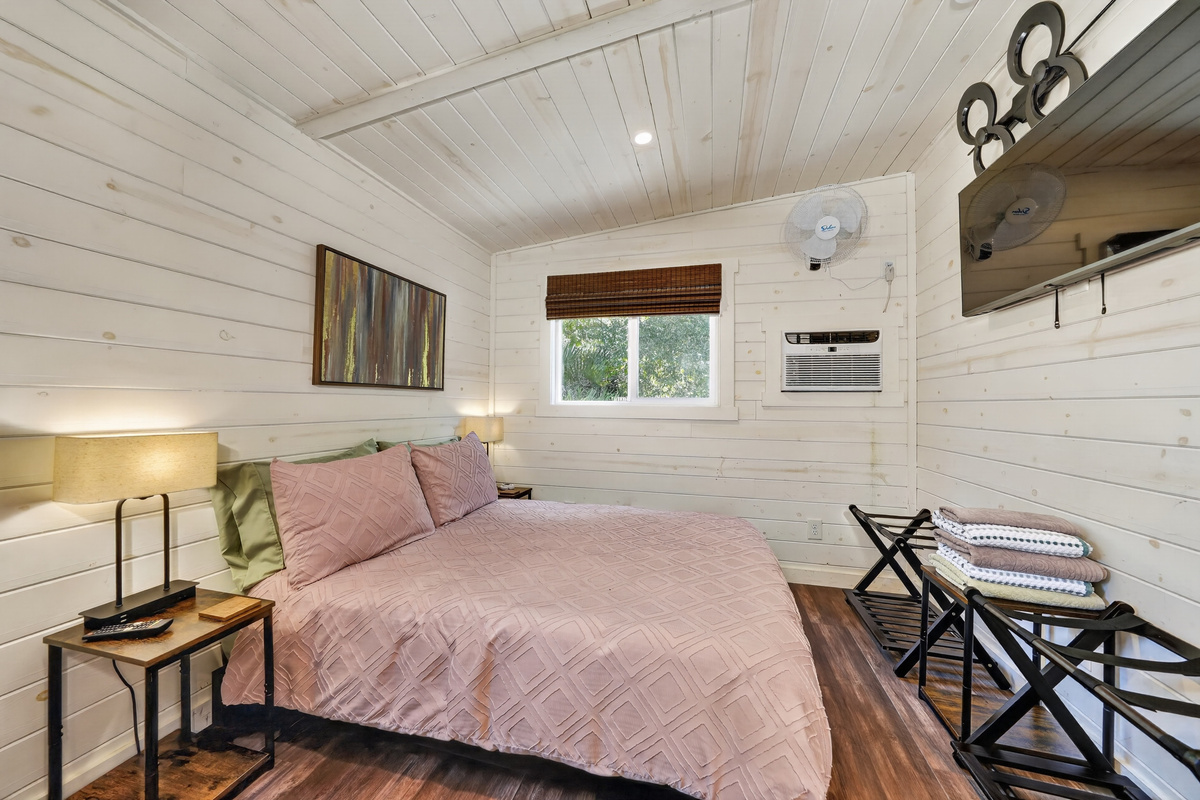 Queen bed, wall-mounted TV, and air conditioning