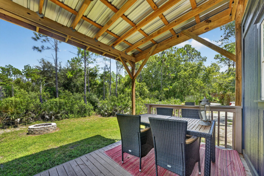 The view from the covered deck — pine, palmetto and the fire pit out front